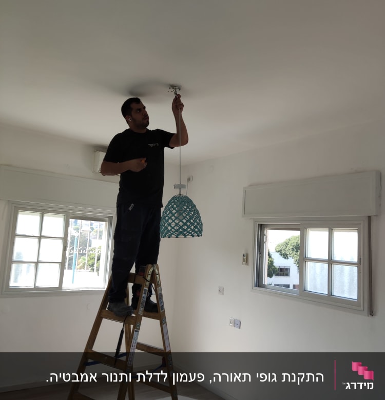 חשמלאי מתקין מנורה מהתקרה בעזרת סולם
